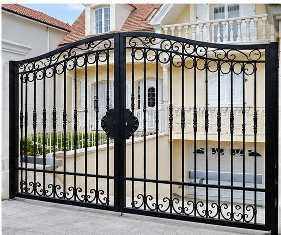 Home 26 Black arched metal driveway gates with decorative vertical bars and scrollwork along the upper and lower rails.