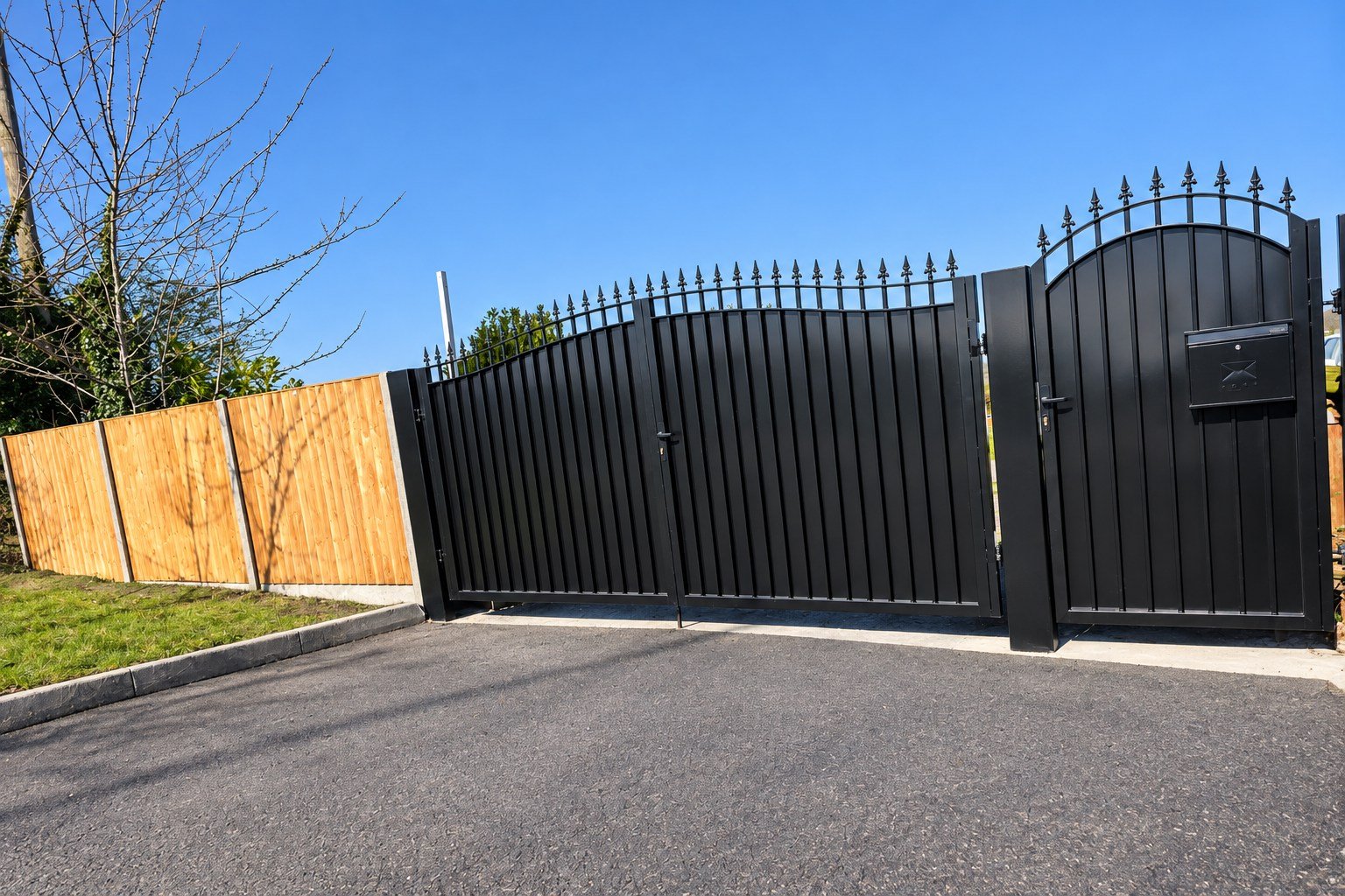 Home 17 Black metal driveway gates with spear finials and a matching arched pedestrian gate.