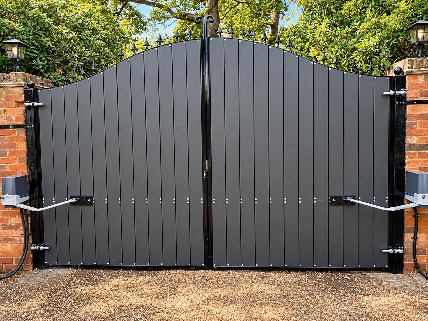 Home 48 Dark grey arched driveway gates with black frames, spear finials and visible opener arms.